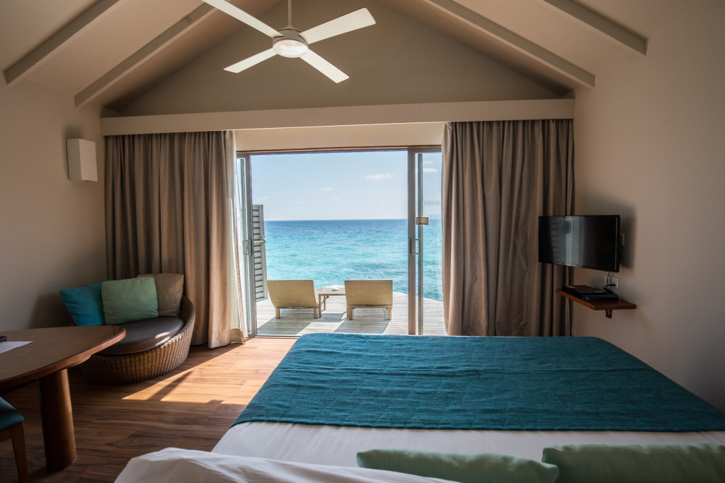 Красивая комната водной виллы на Мальдивах c видом на бирюзовый океан