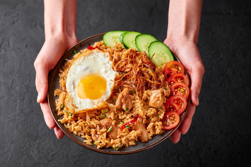 Наси-Горенг - блюдо индонезийской кухни с жасминовым рисом, куриным мясом, жареным луком, яйцом и овощами