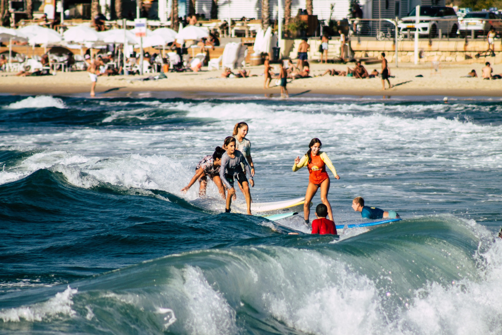 Начинающие серферы практикуются недалеко от берега пляжа Хилтон в Тель-Авиве