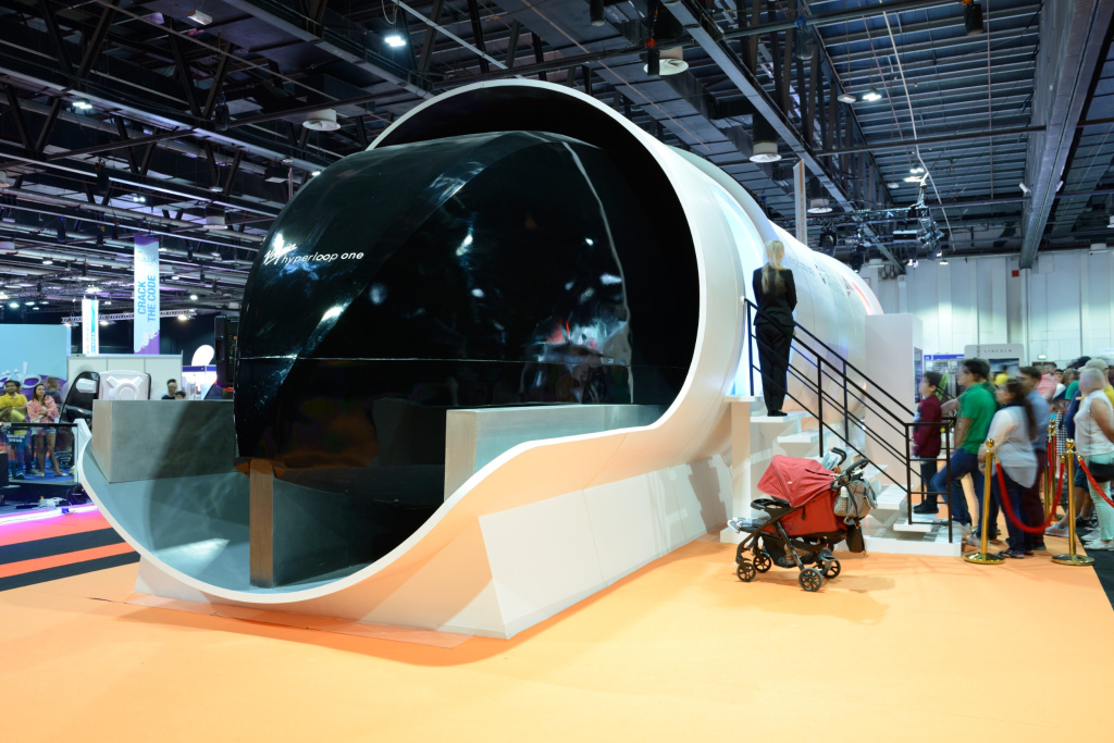 Прототип системы сверхзвукового поезда Virgin Hyperloop One и люди в очереди на тестирование салона вагона на автосалоне в Дубае в 2020 г.